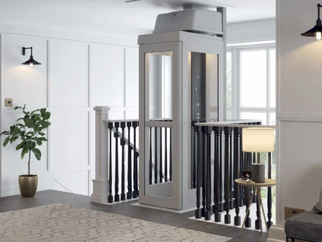 Pollock Home Elevator at the second floor landing blending with dark railing and wooden floor