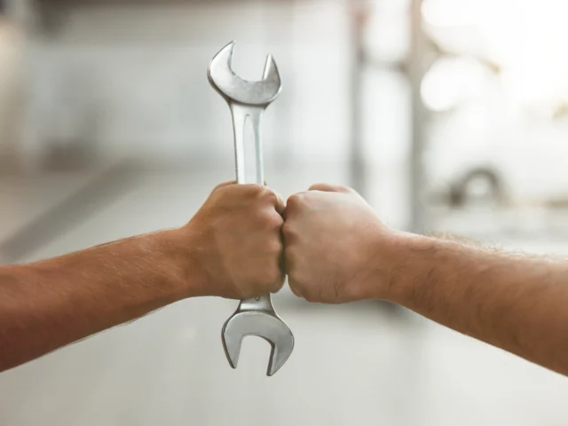 two men fist bumping one with car spanner.
