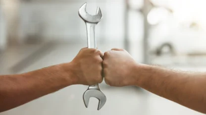 two men fist bumping one with car spanner.