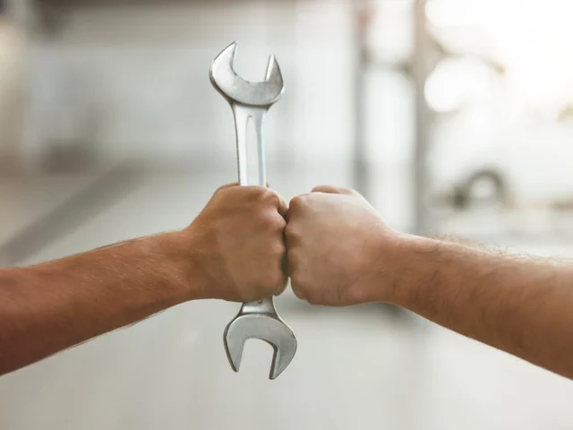 two men fist bumping one with car spanner.