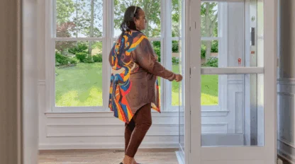 Older woman opens an elevator door in her living room