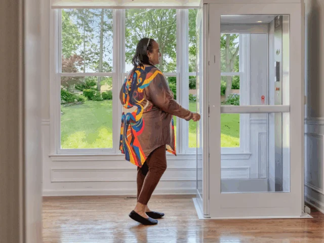 Older woman opens an elevator door in her living room