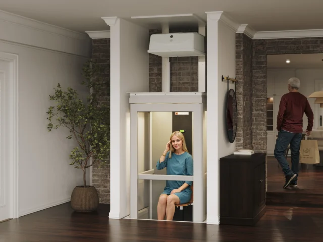 Young woman with blonde, long hair sits on the Pollock elevator as it moves between floors.