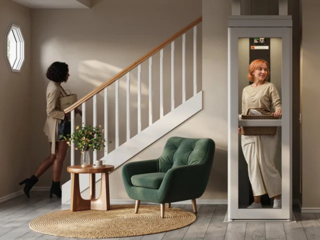 A woman with dark hari climbs the stairs as a woman with lighter hair uses a residential elevator