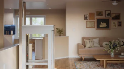 Modern pitless residential elevator installed in an open-concept living room, featuring a compact self-supporting white cabin with glass panels, integrated into hardwood flooring for seamless multi-level home accessibility.