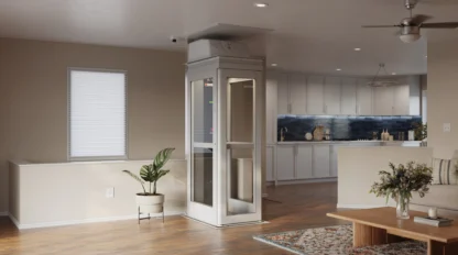 A white, compact residential elevato sits at the lower level of a bright home, beside a clean kitchen.