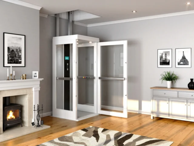 A white, medium-sized home elevator sits in the corner of a living room with its door open.