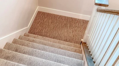 Carpeted residential staircase with a handrail, highlighting home safety and fall prevention for older adults.