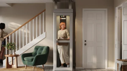 A woman in white stands in her lit home elevator, which sits between stairs and a closet.