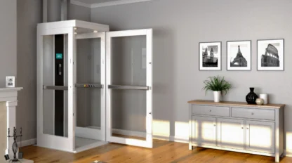 A while home elevator sits in the corner of a well lit room with grey walls and a hardwood floor, its door open.
